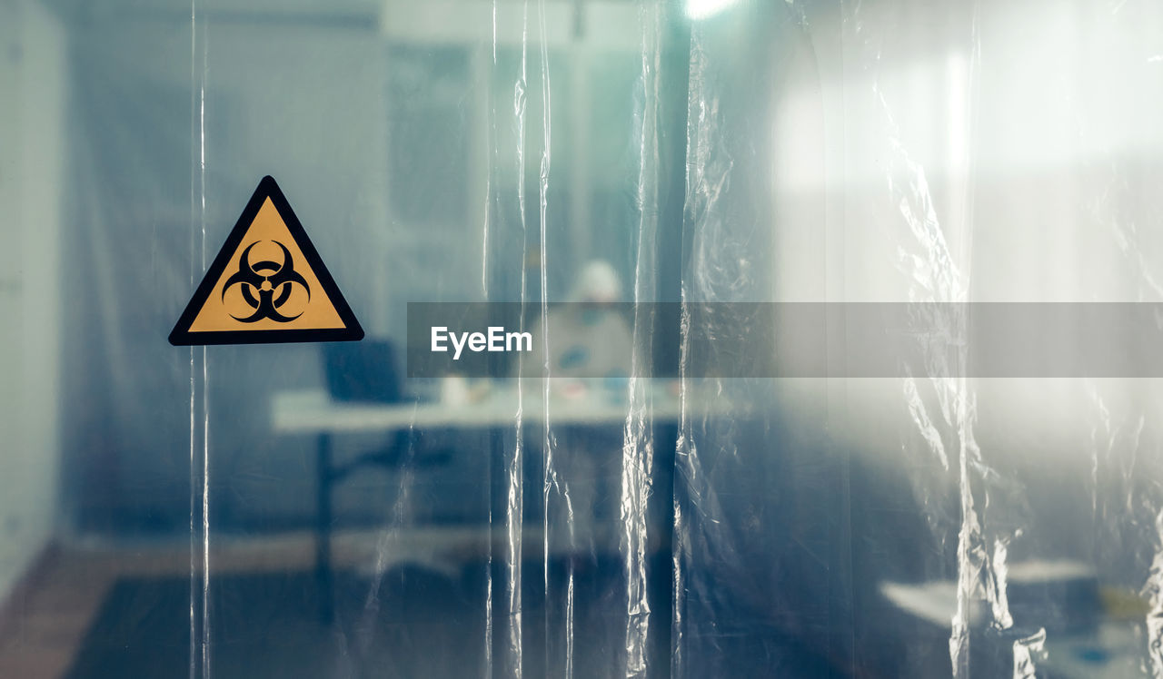 Scientist working in hospital seen through plastic curtain