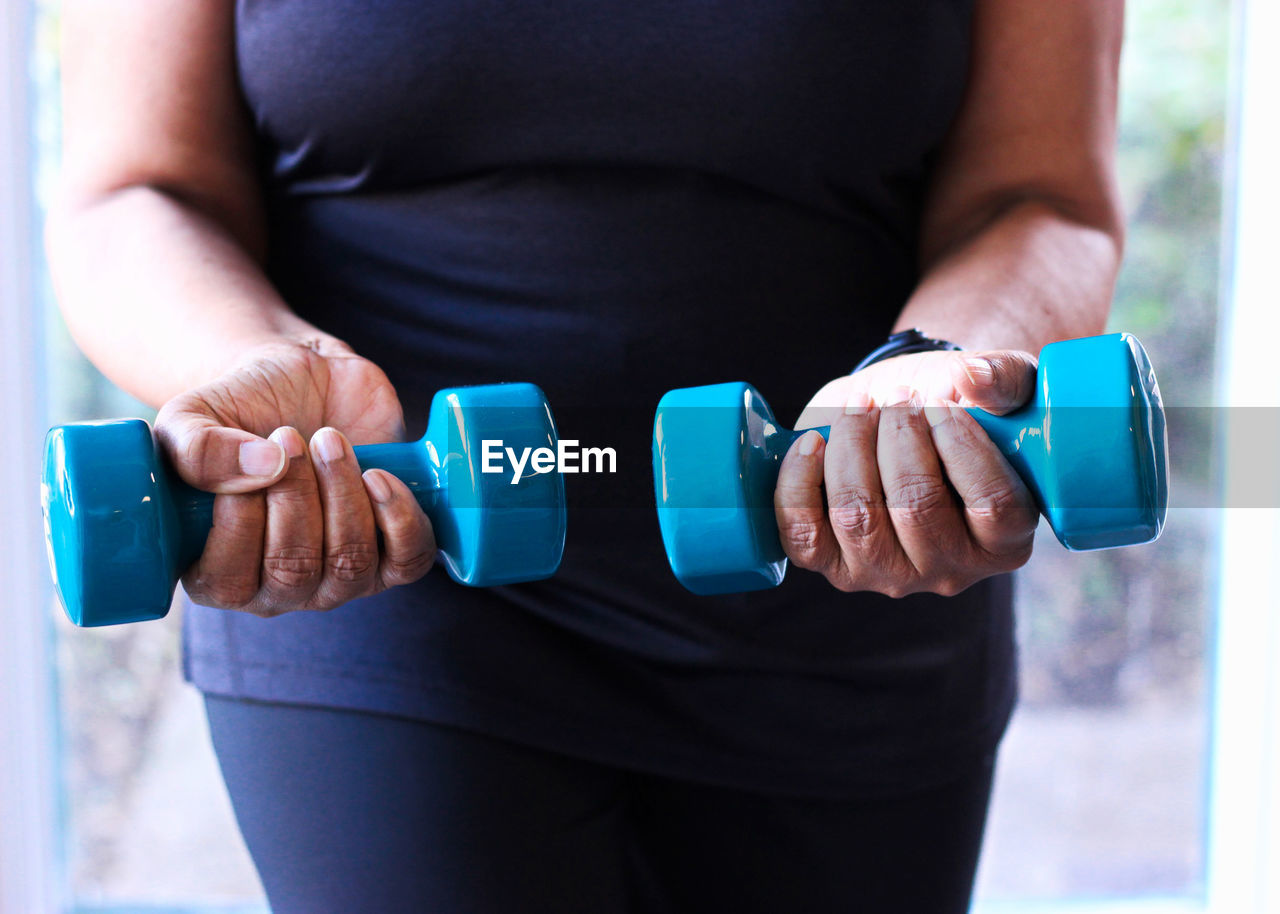 Close-up of senior black woman strength training with dumbbells for health and fitness.