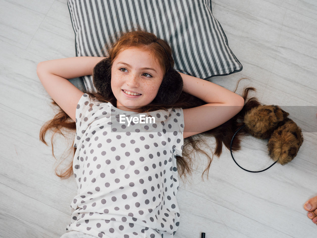 High angle view of smiling girl lying on floorboard at home