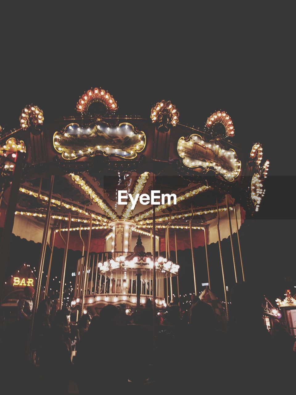 Low angle view of illuminated carousel against sky at night