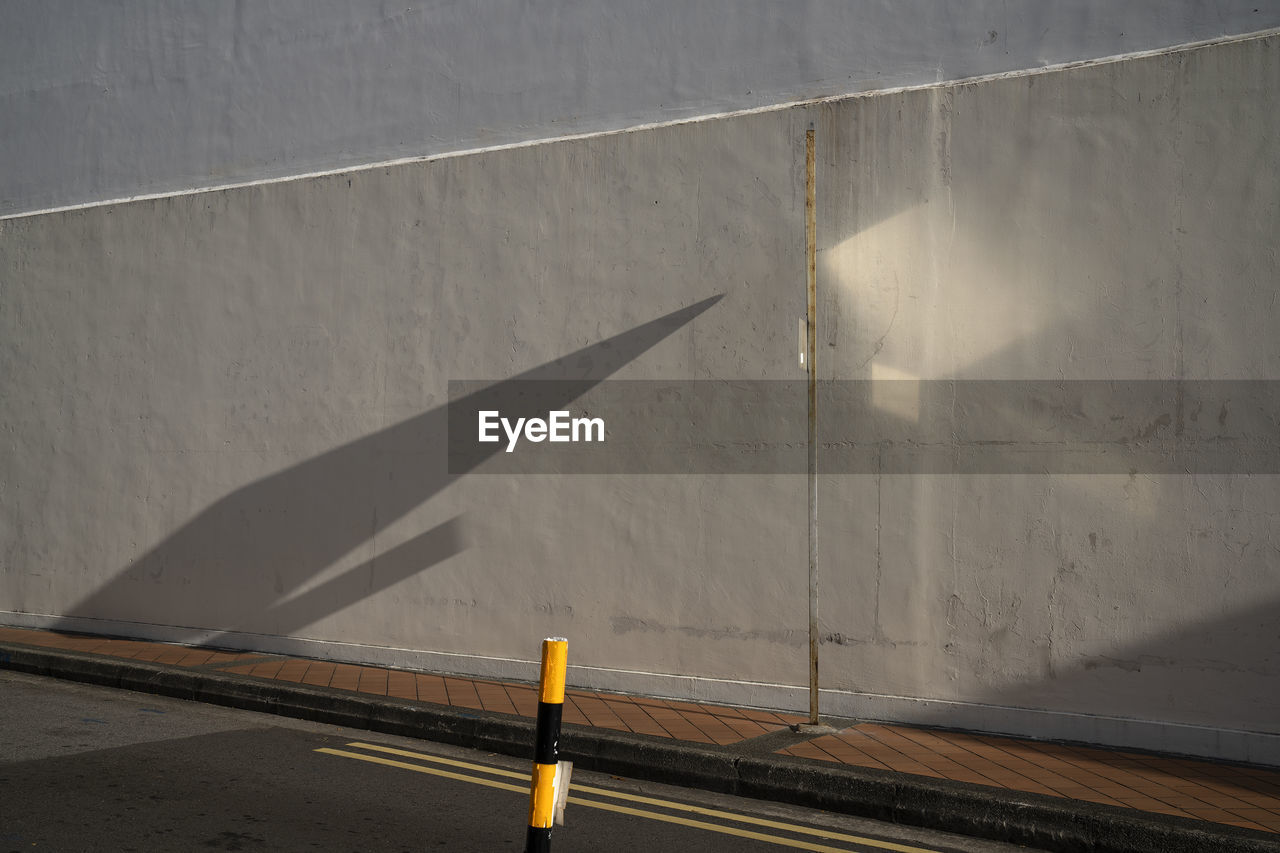 Shadow of traffic sign on road against wall