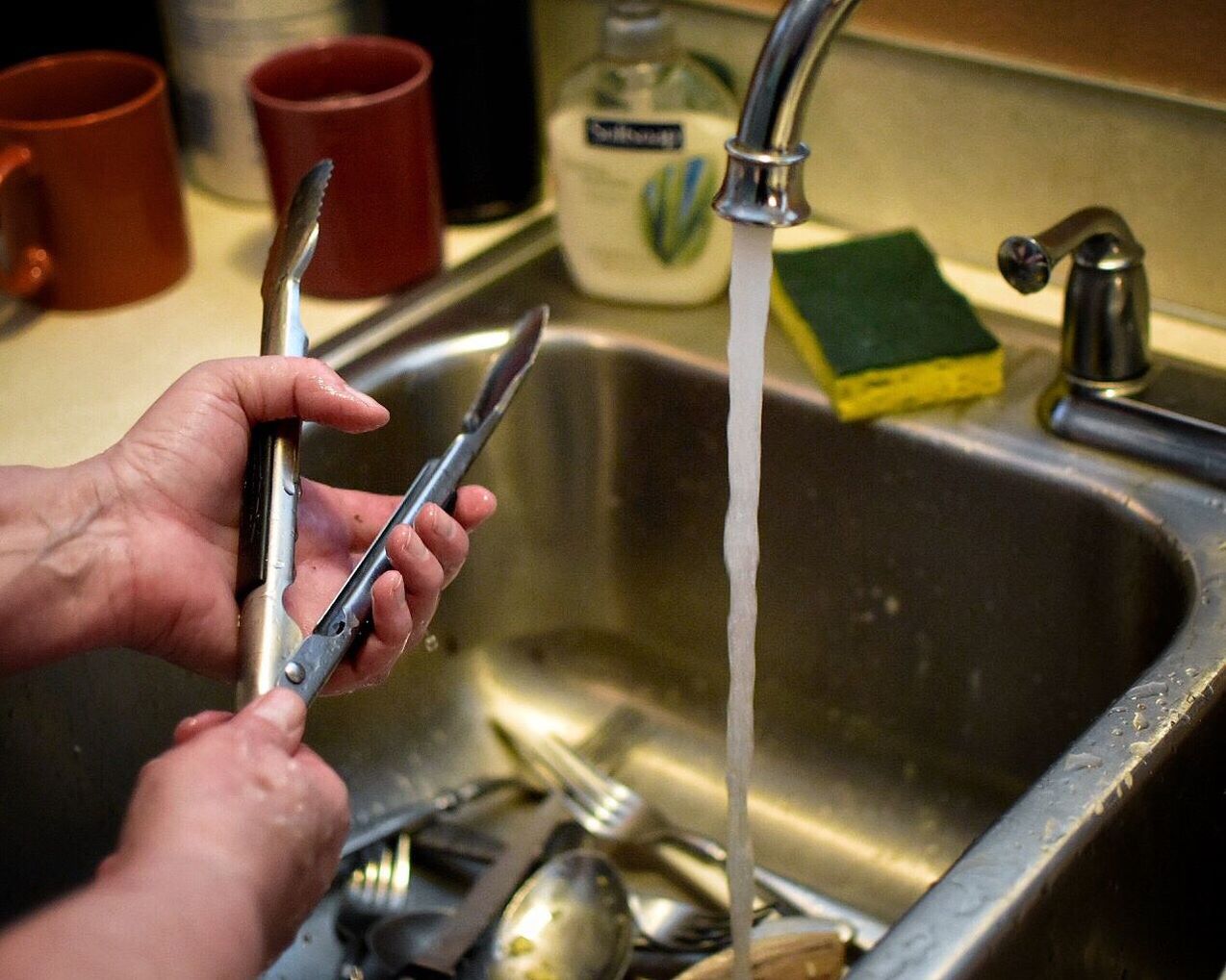 CLOSE-UP OF HAND HOLDING FAUCET