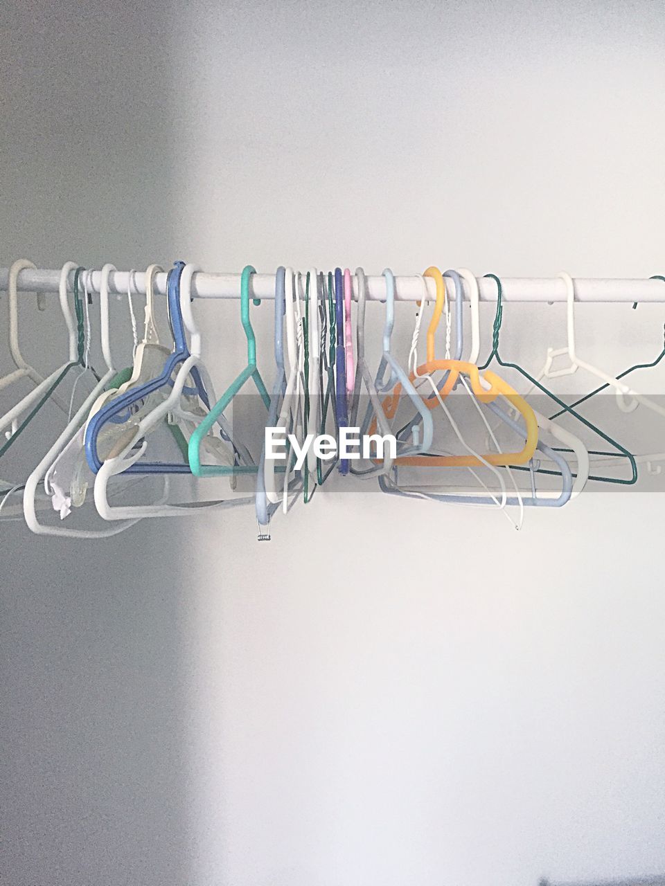 Colorful coathangers hanging on rack against wall at home