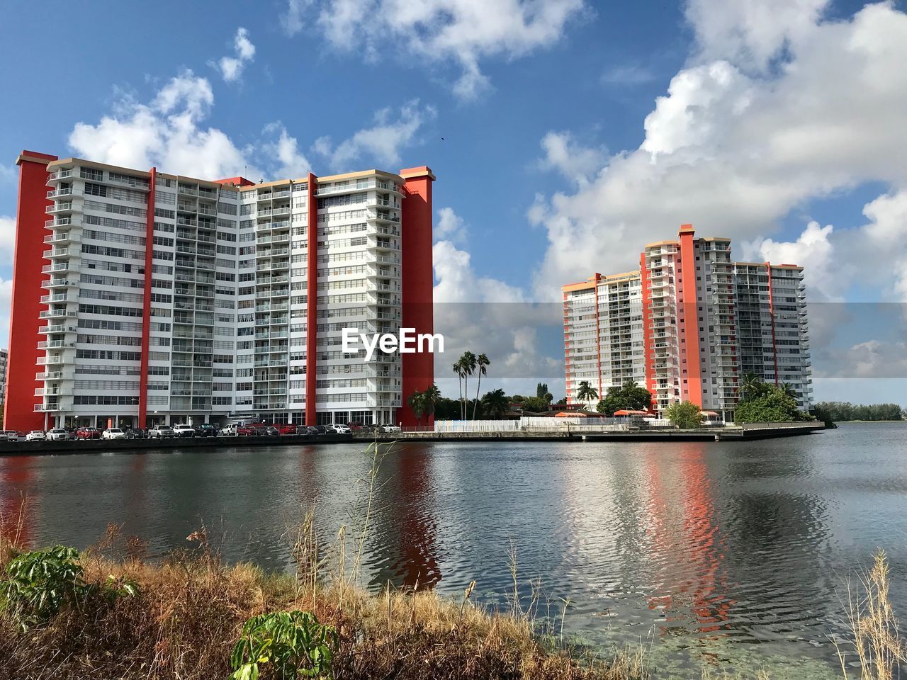 Buildings by river against sky in city