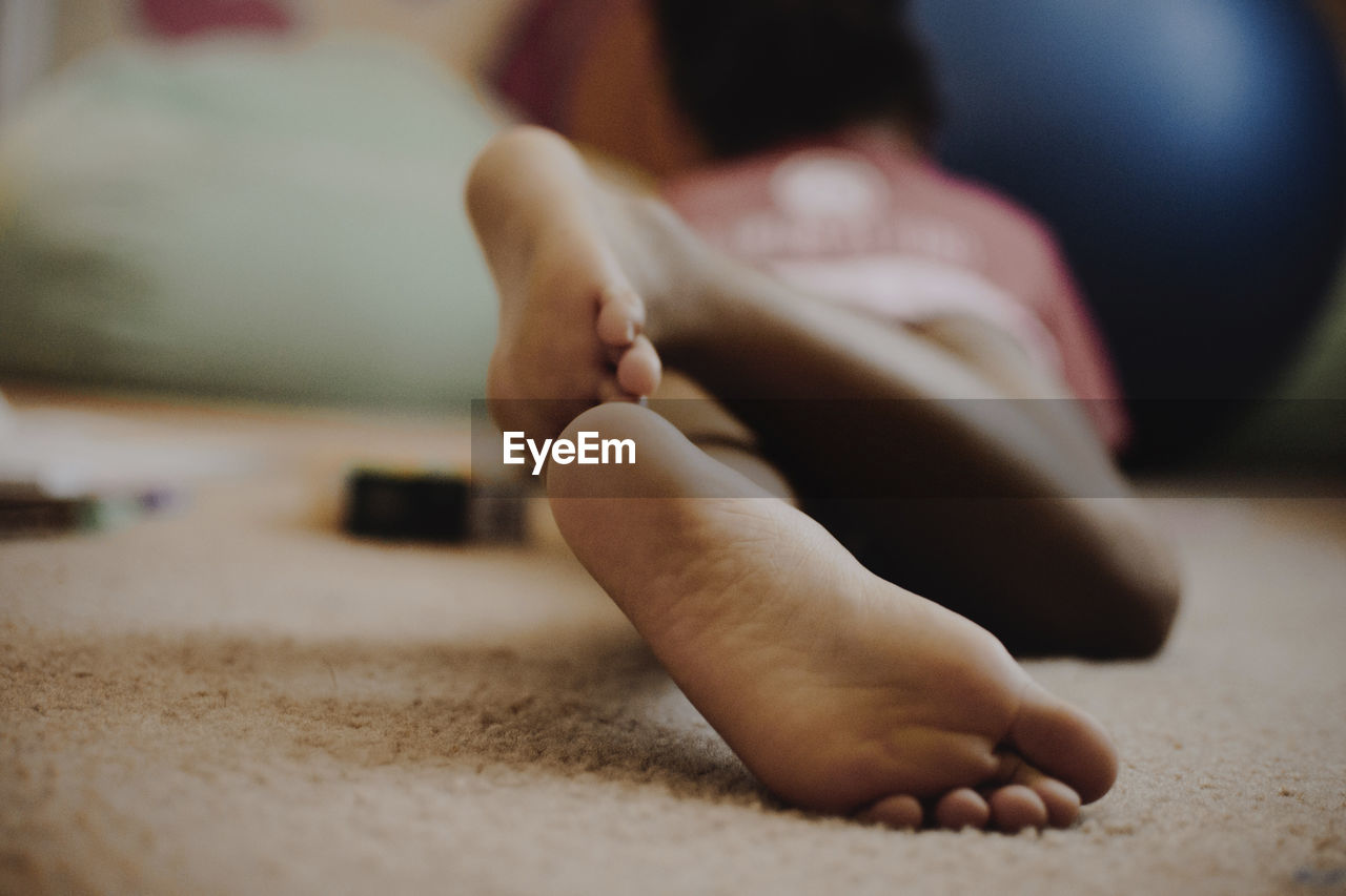 Rear view of girl lying on floor at home