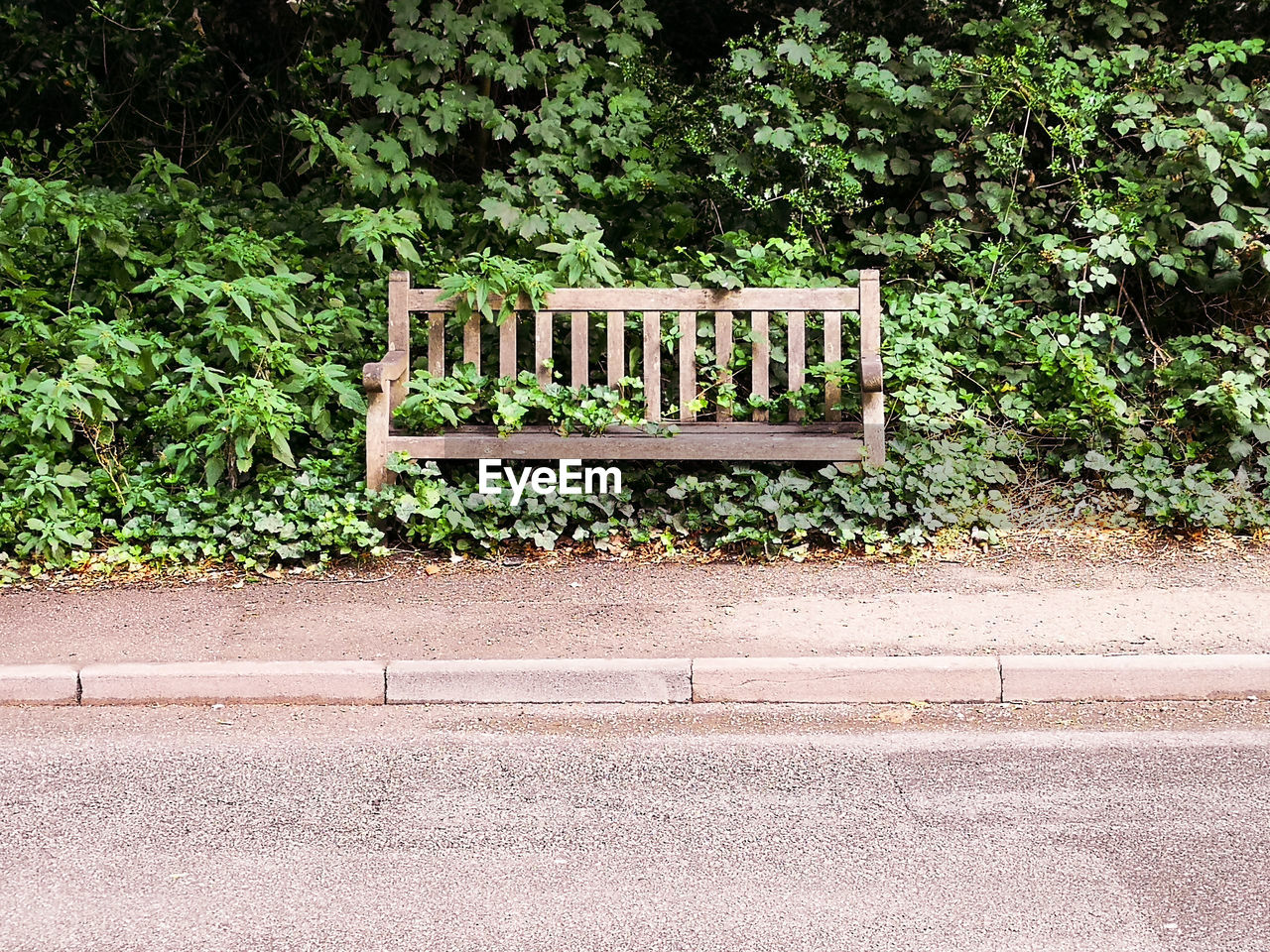 EMPTY BENCH BY ROAD IN CITY