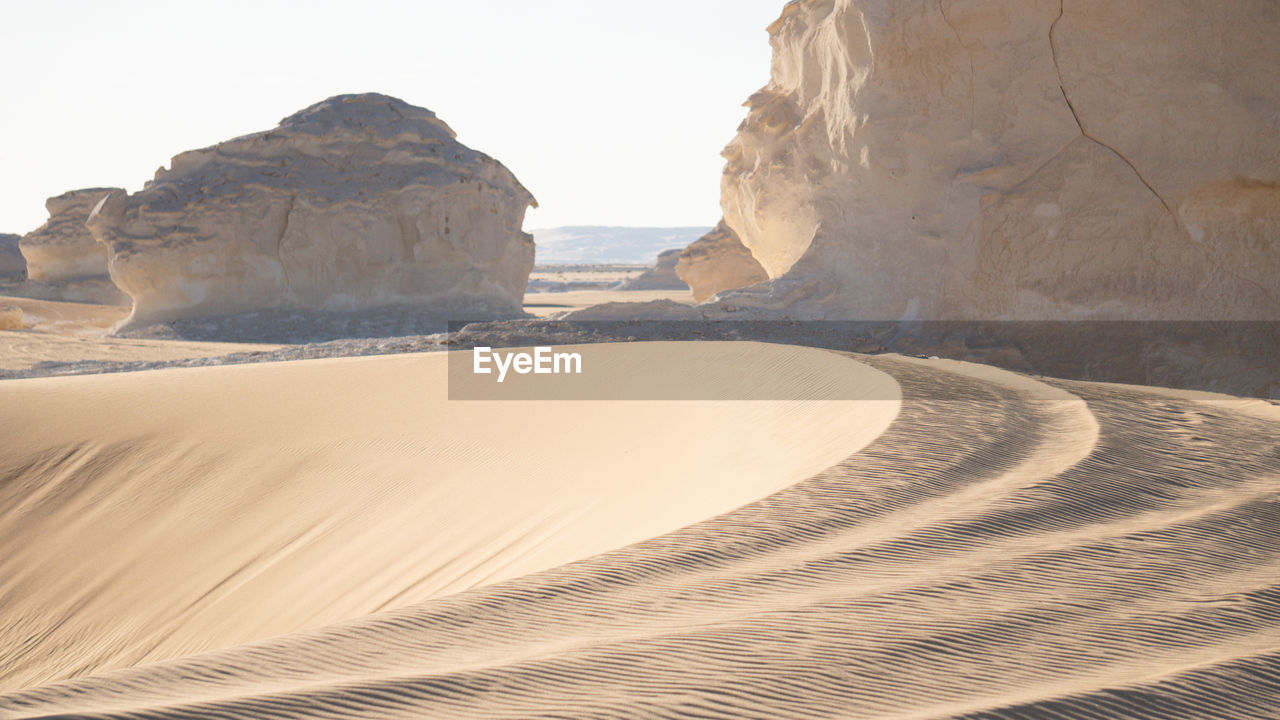 sand, land, landscape, scenics - nature, natural environment, desert, environment, nature, sand dune, rock, wadi, beauty in nature, travel, travel destinations, rock formation, sky, no people, non-urban scene, tranquility, climate, arid climate, erg, outdoors, day, geology, physical geography, tranquil scene, tourism, remote, clear sky, extreme terrain, sunlight, formation, dry