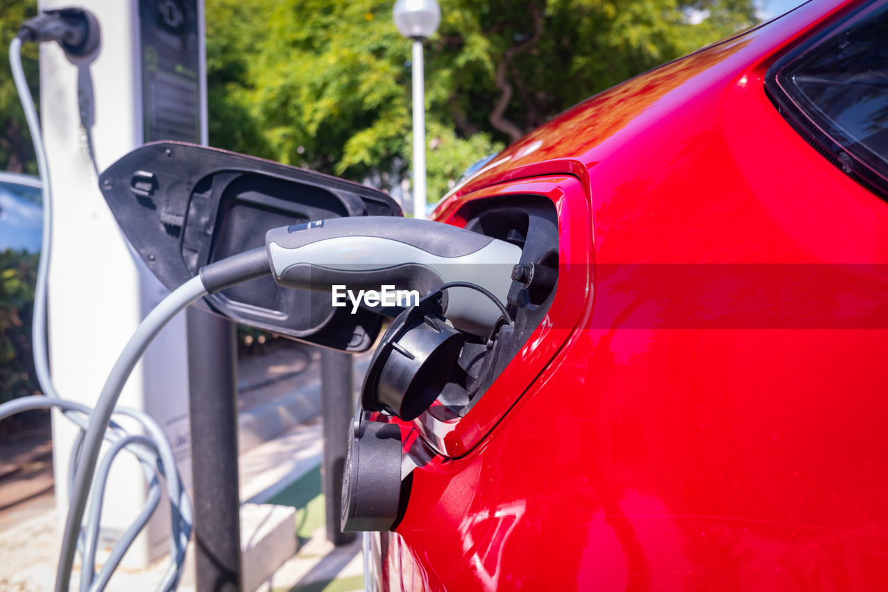 Red car recharging its lithium electric batteries at a free public station.