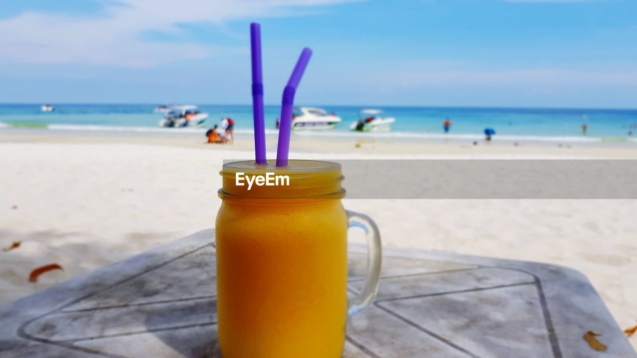 CLOSE-UP OF DRINK ON BEACH