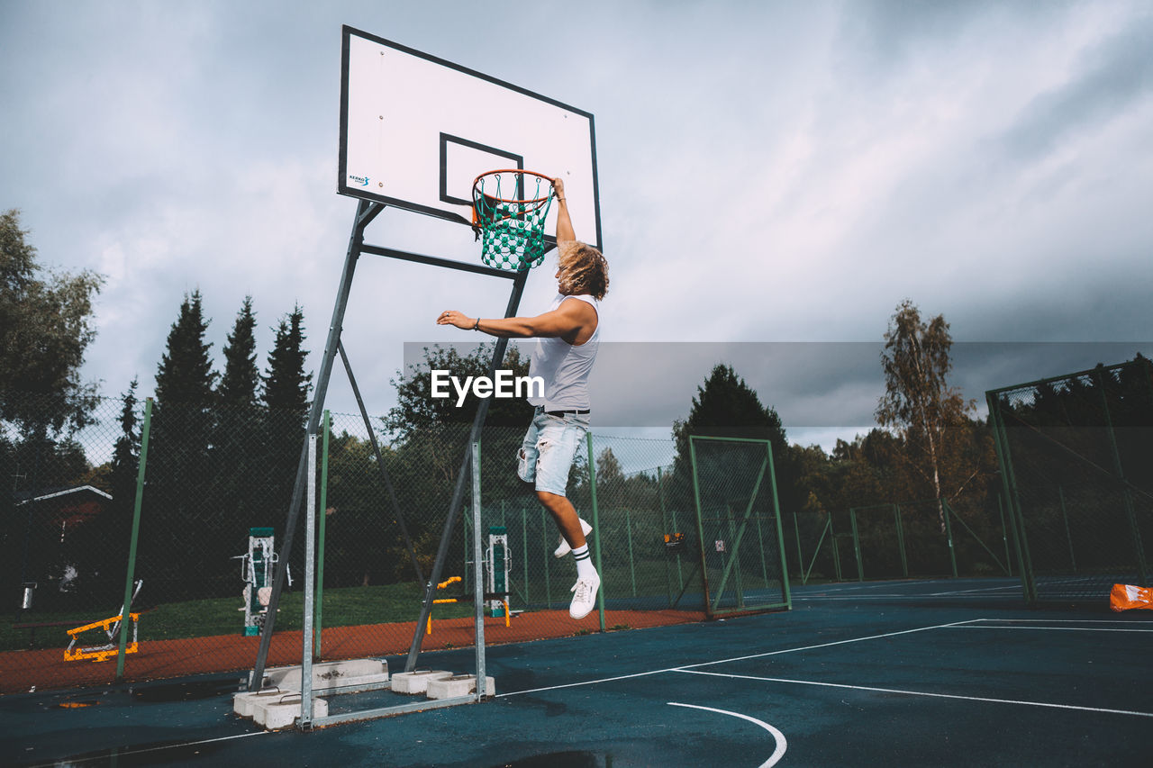 MAN PLAYING BASKETBALL HOOP