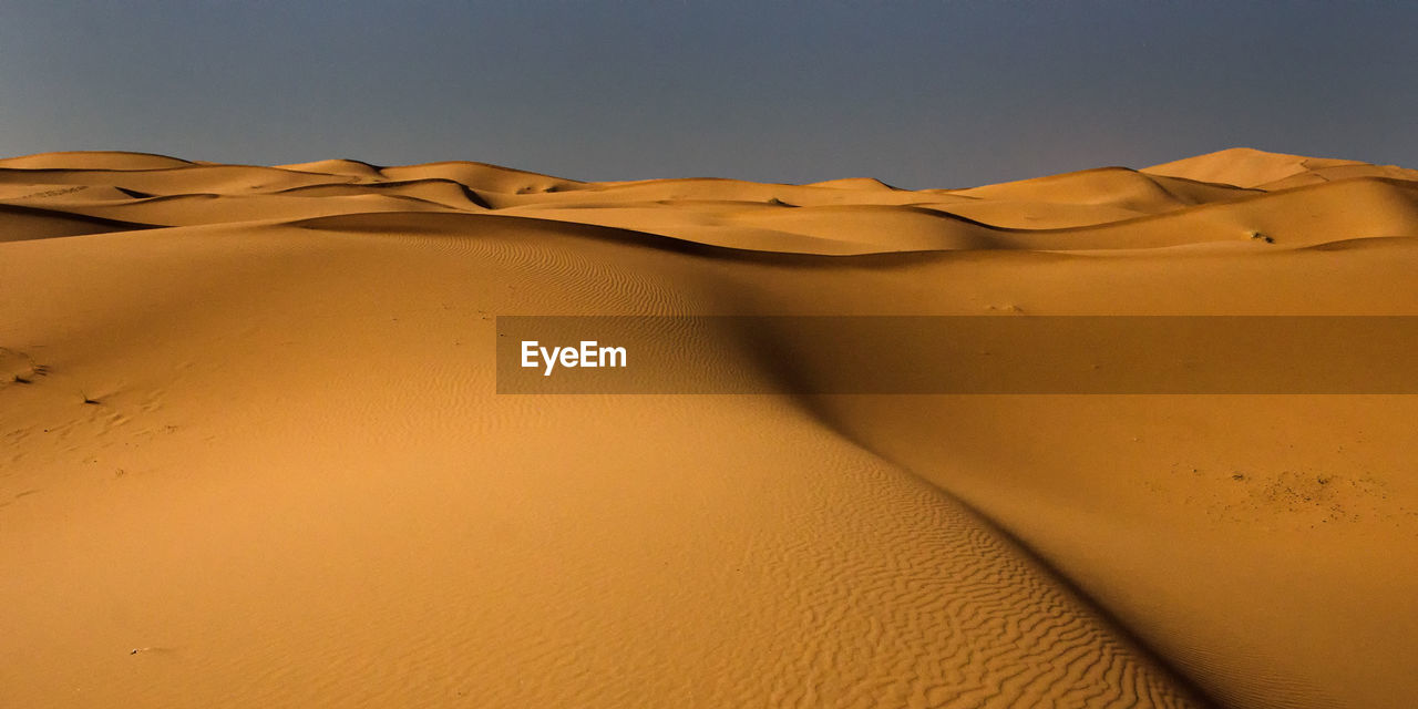 Sand dunes in desert against clear sky