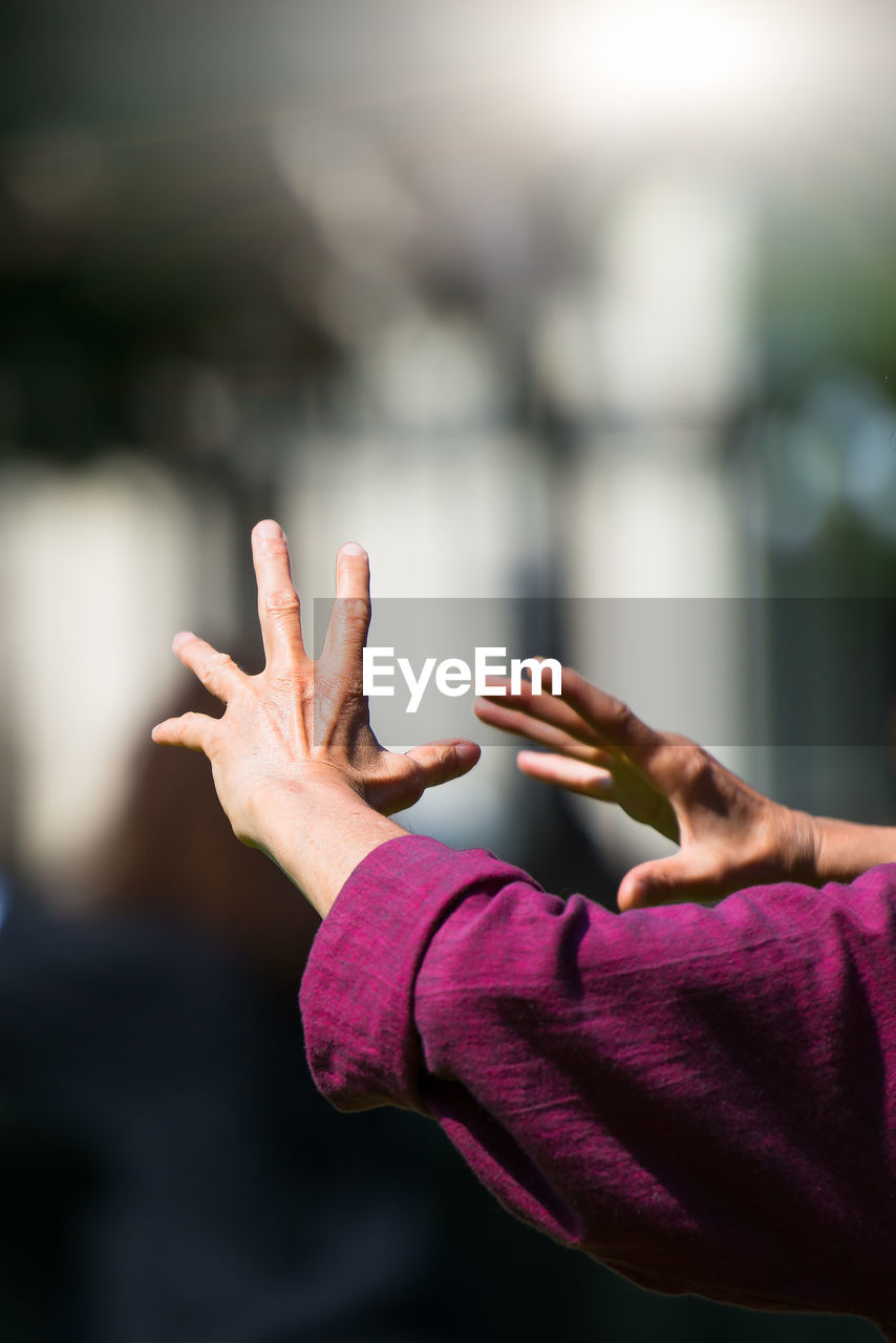 Cropped hand of woman gesturing against blurred background