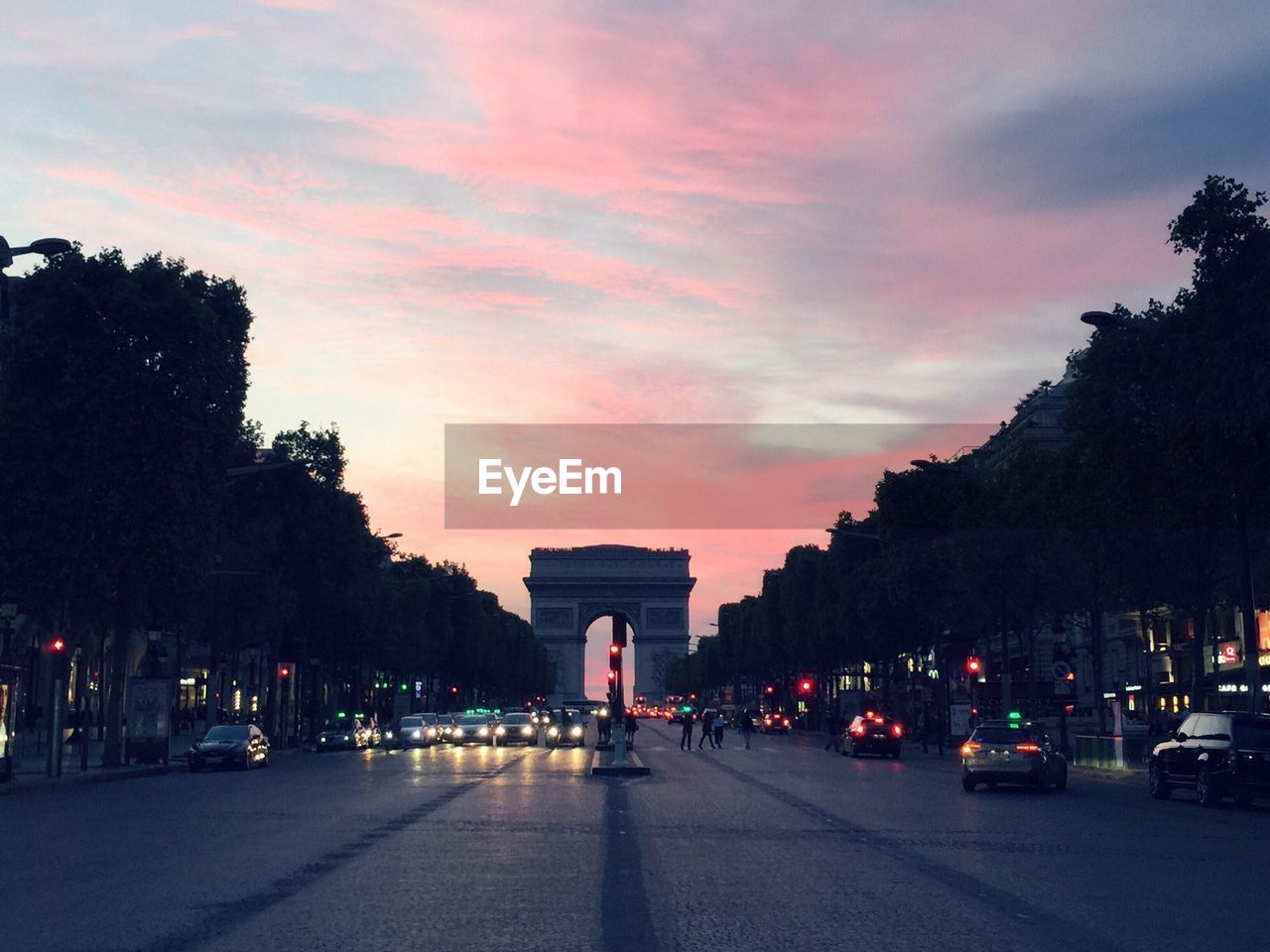 Road leading towards triumphal arch in city during sunset