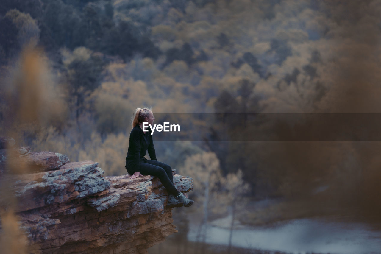 Side view of woman sitting on rock