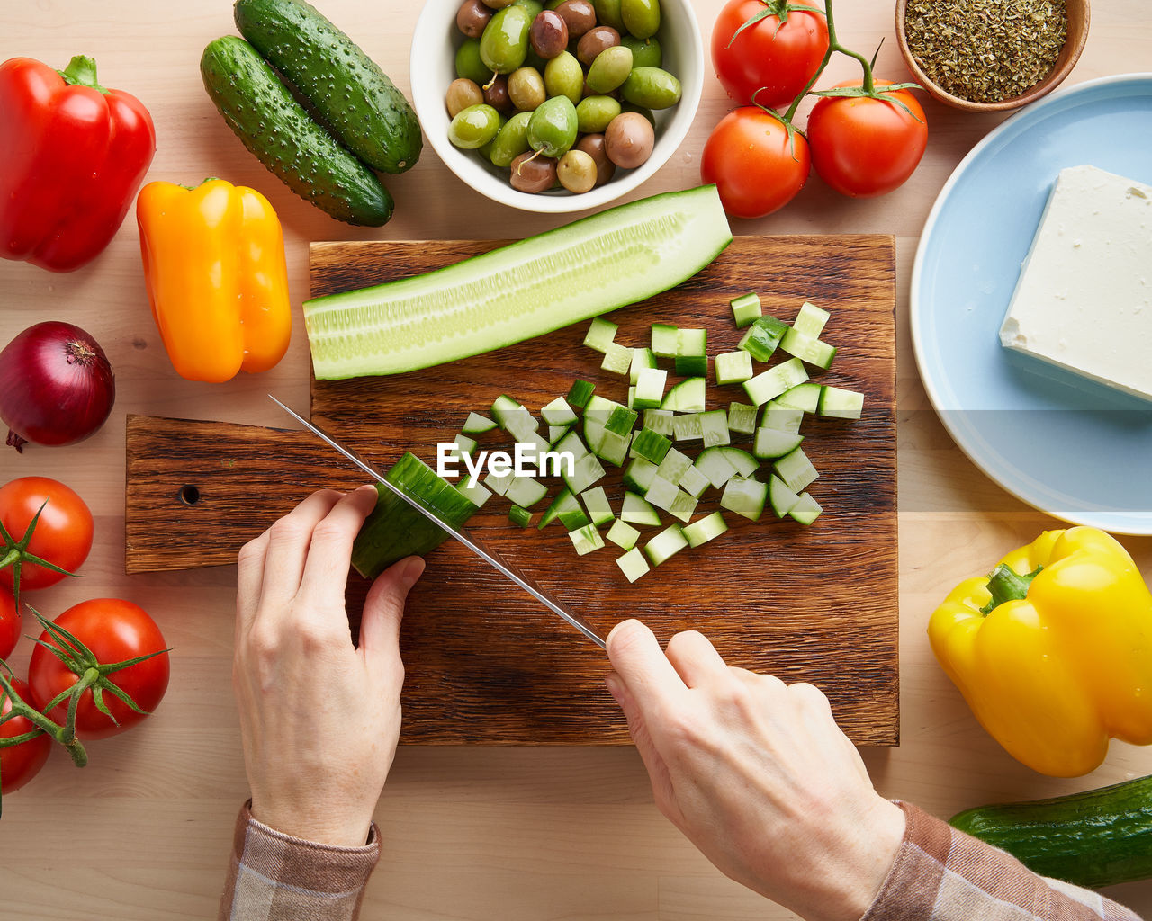 Step by step recipe for salad horiatiki, wooden board for cutting vegetables and ingredients. hands 