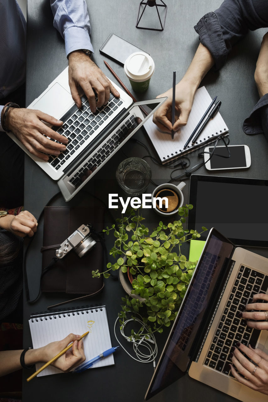 Directly above shot of business team working at table in creative office