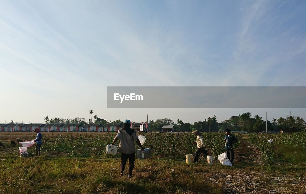 REAR VIEW OF PEOPLE WALKING ON FIELD