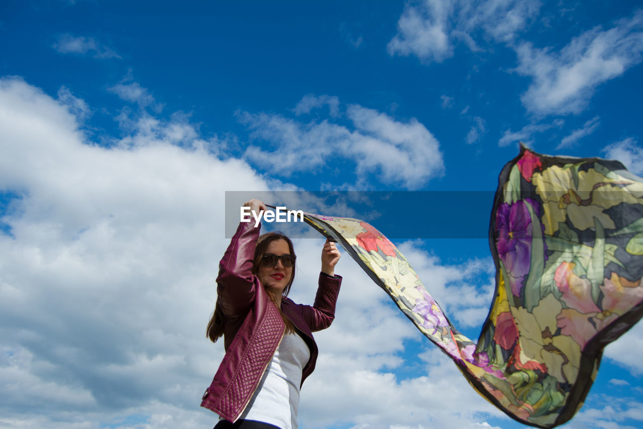 WOMAN WITH UMBRELLA STANDING AGAINST SKY