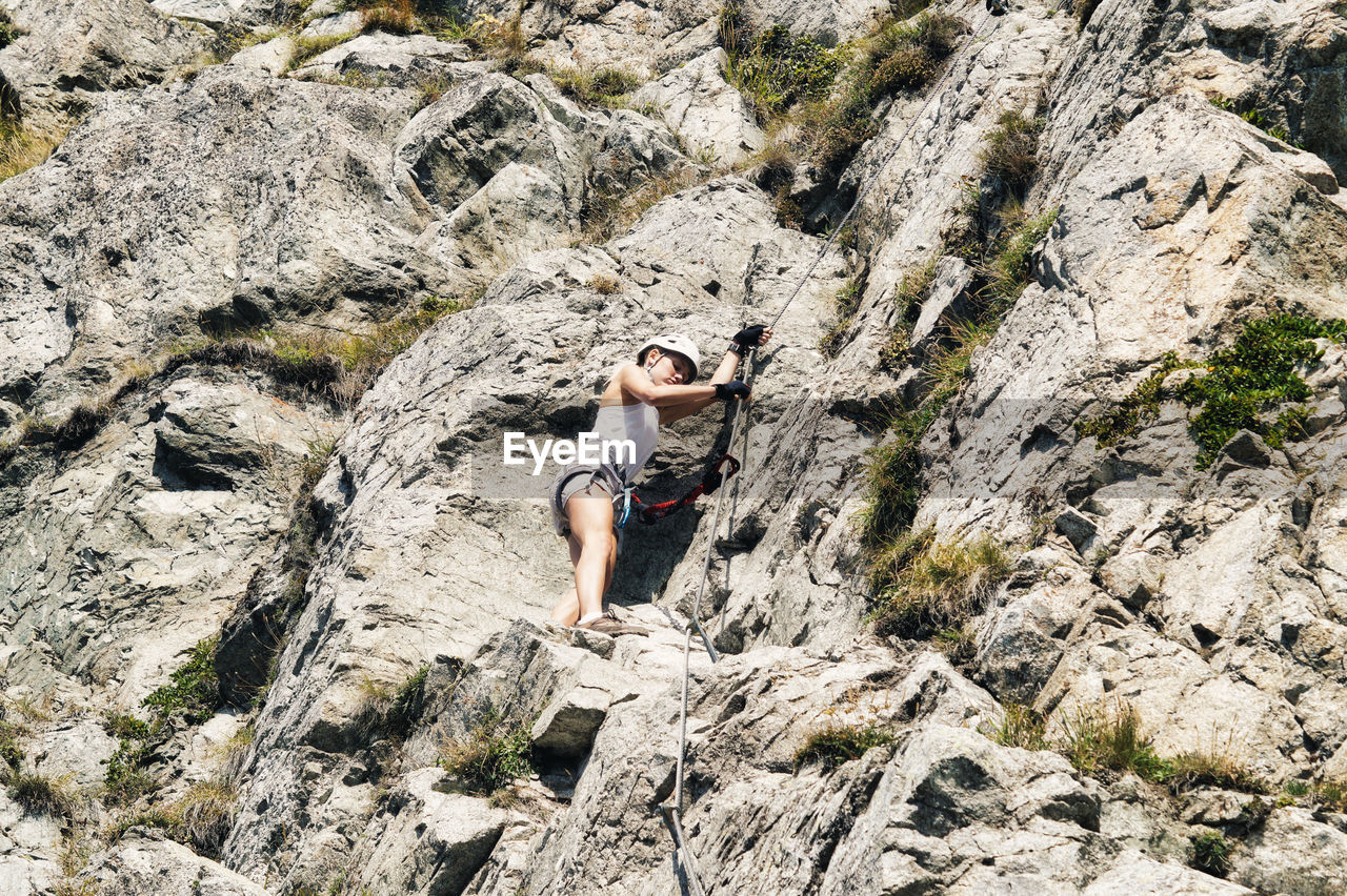 Low angle view of woman climbing rock