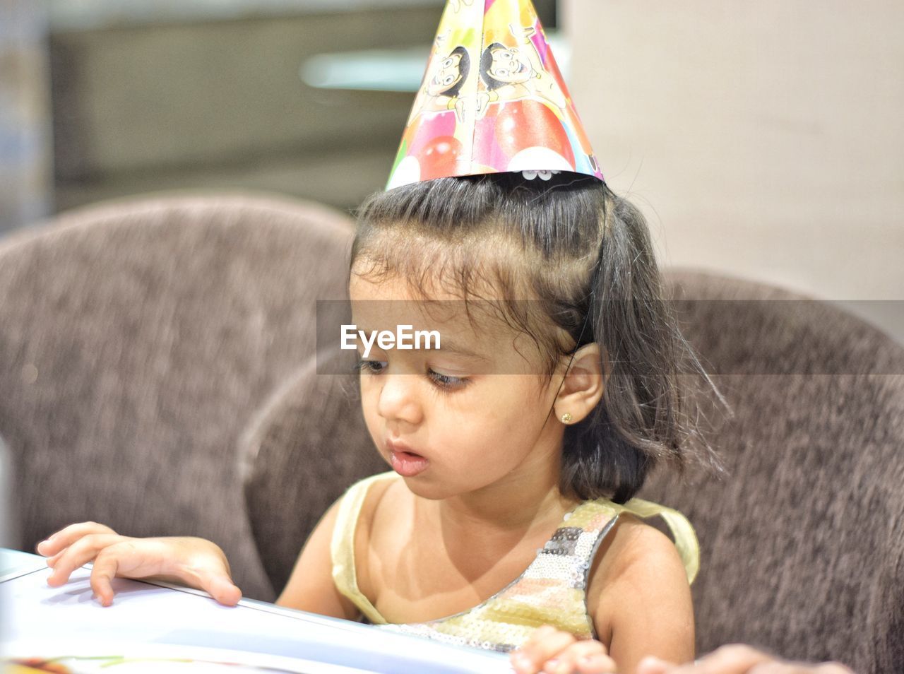 Cute girl wearing party hat sitting at home