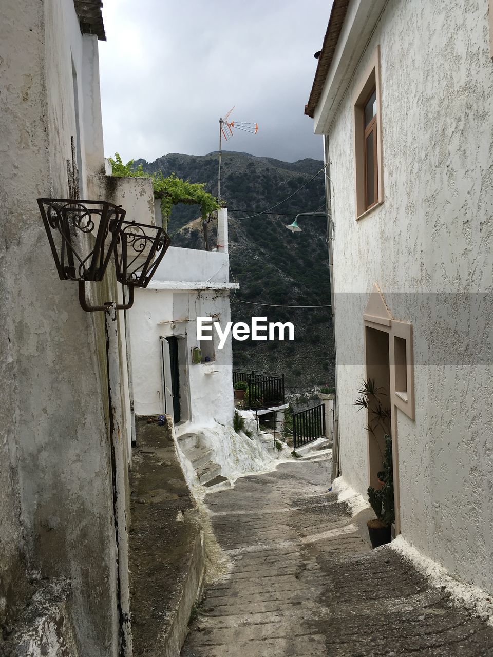 ALLEY AMIDST HOUSES AGAINST SKY