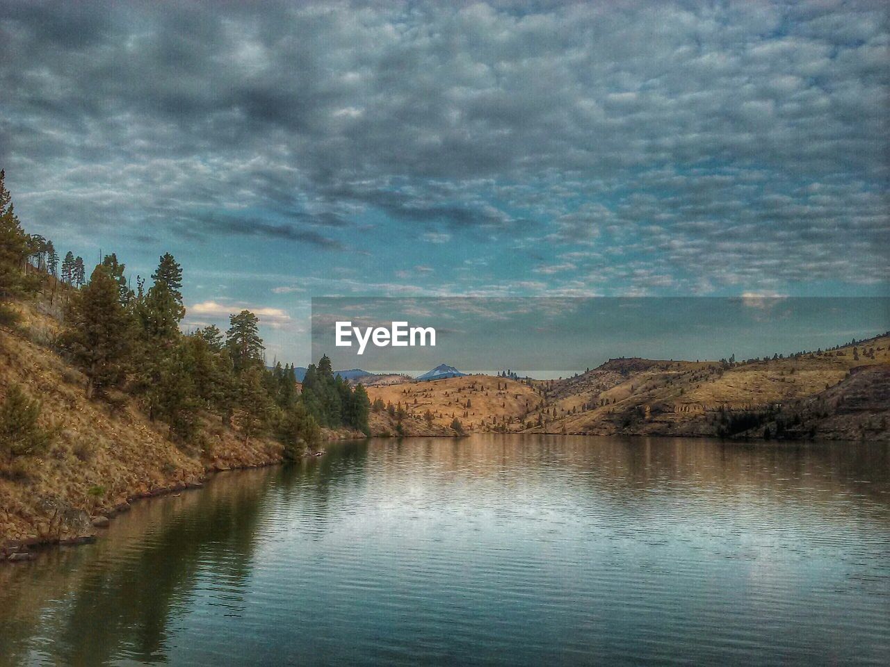 Scenic view of lake by mountains against cloudy sky