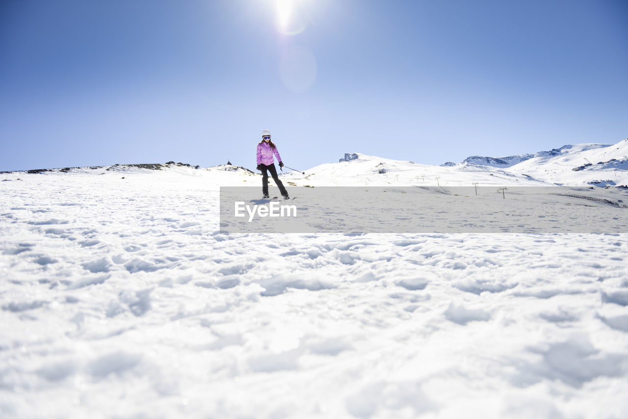 Woman skiing under blue sky, sierra nevada, andalusia, spain