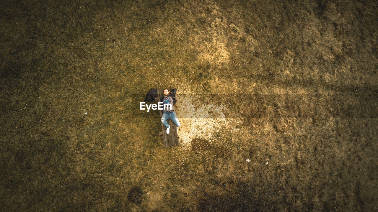 Aerial view of man lying on bench at grassy field