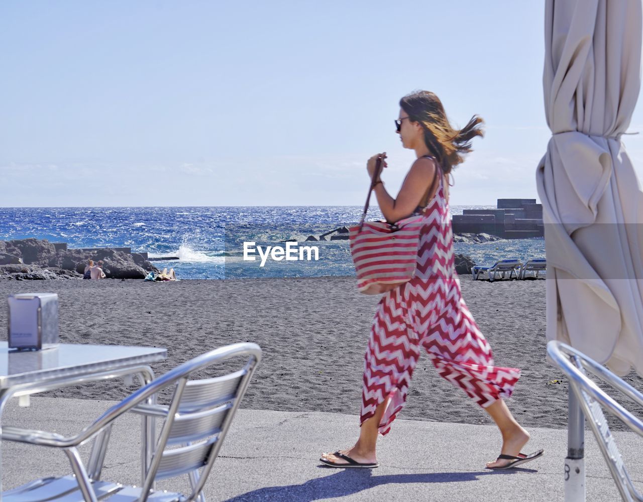 REAR VIEW OF WOMAN STANDING AT BEACH