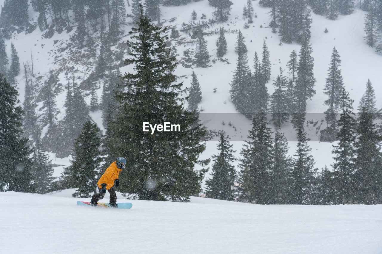 Full length of man snowboarding on snow covered land during winter