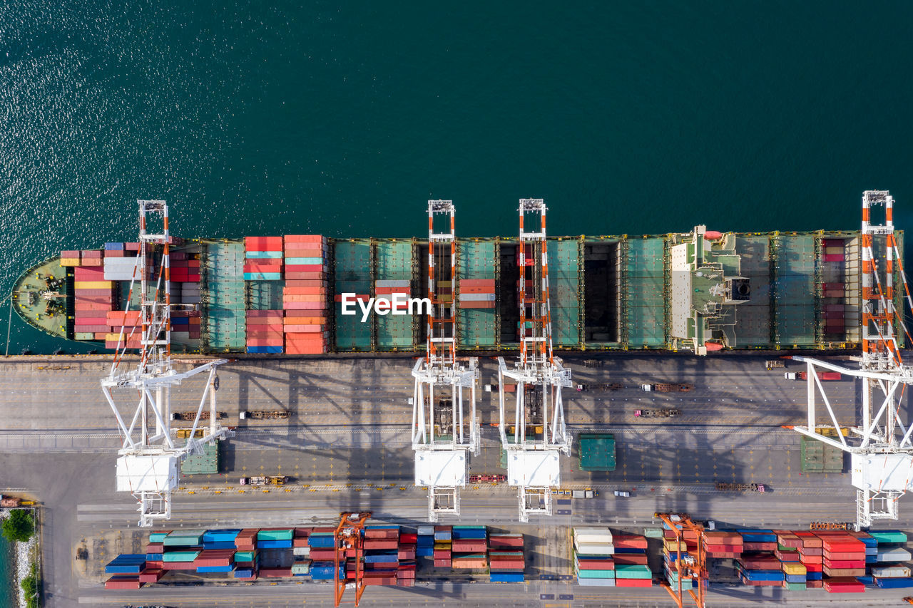 High angle view of commercial dock and shipping containers loading against sea