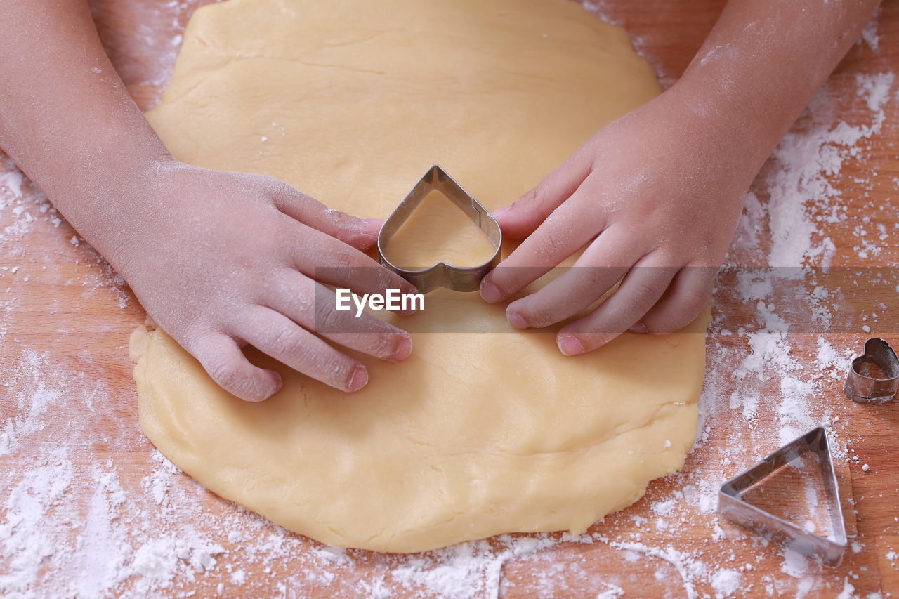 Cropped image of hands making heart shape cookies during christmas