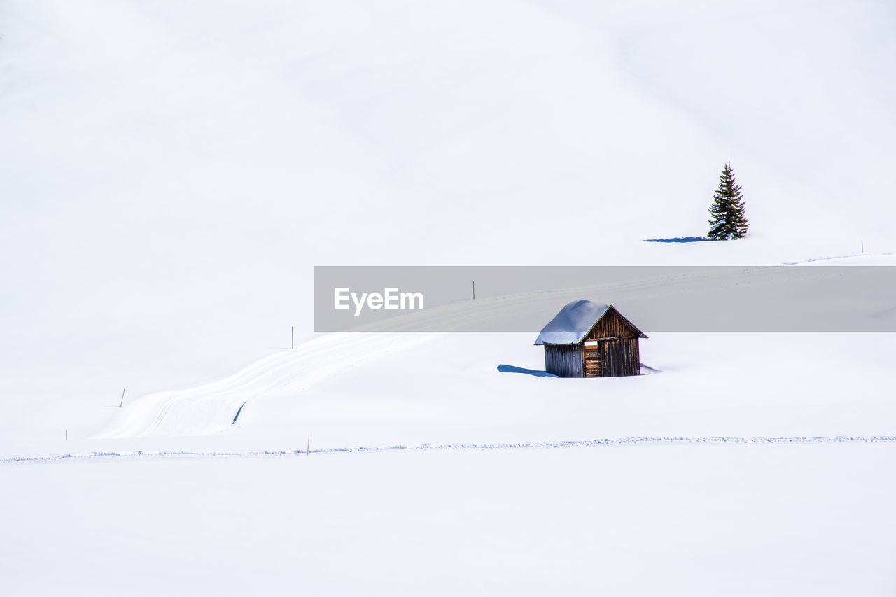 House on snow covered land against sky