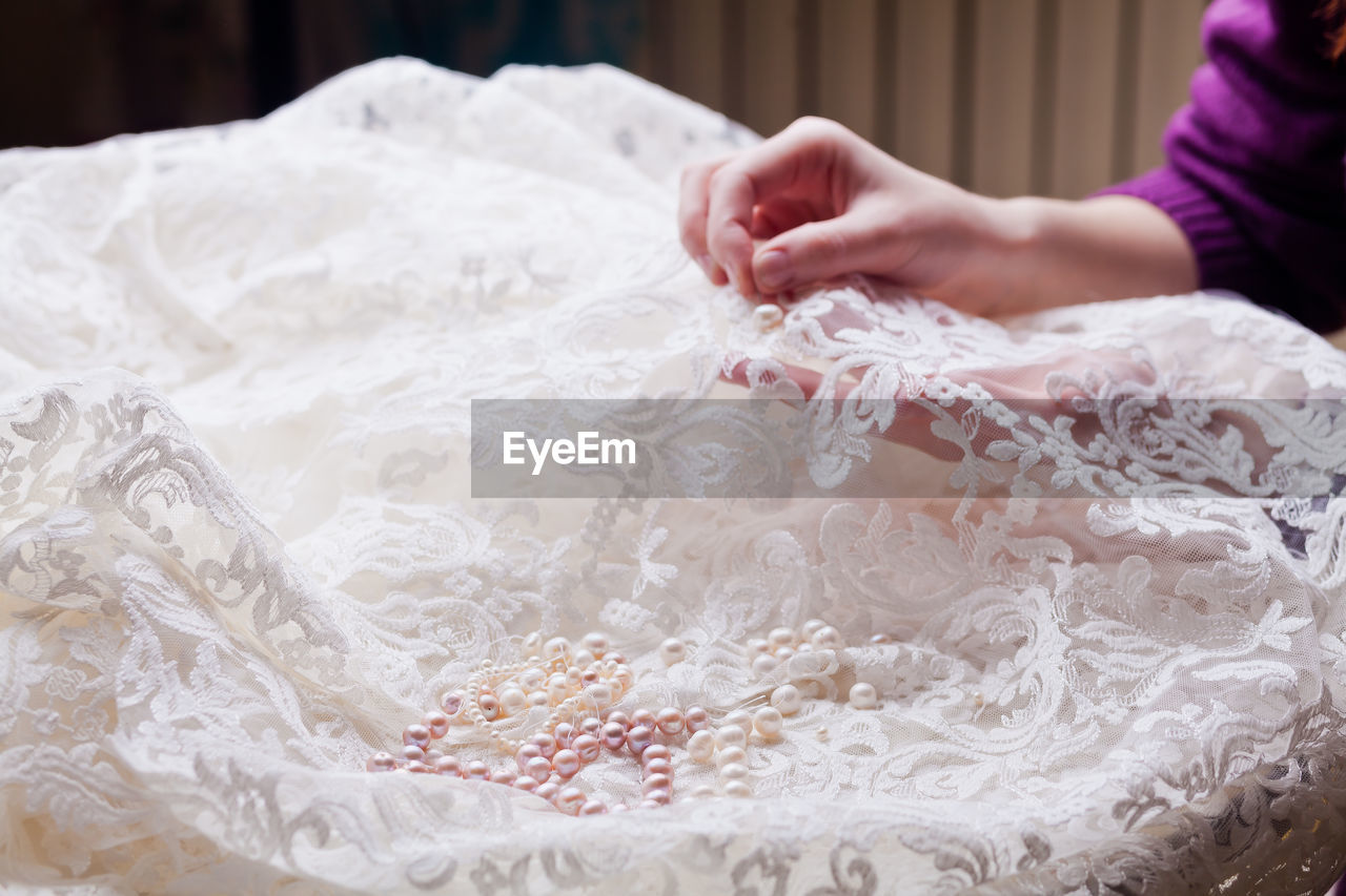 Cropped hands of woman stitching wedding dress