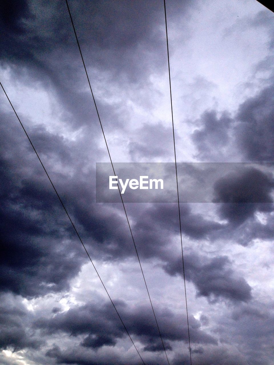 Low angle view of cables against cloudy sky