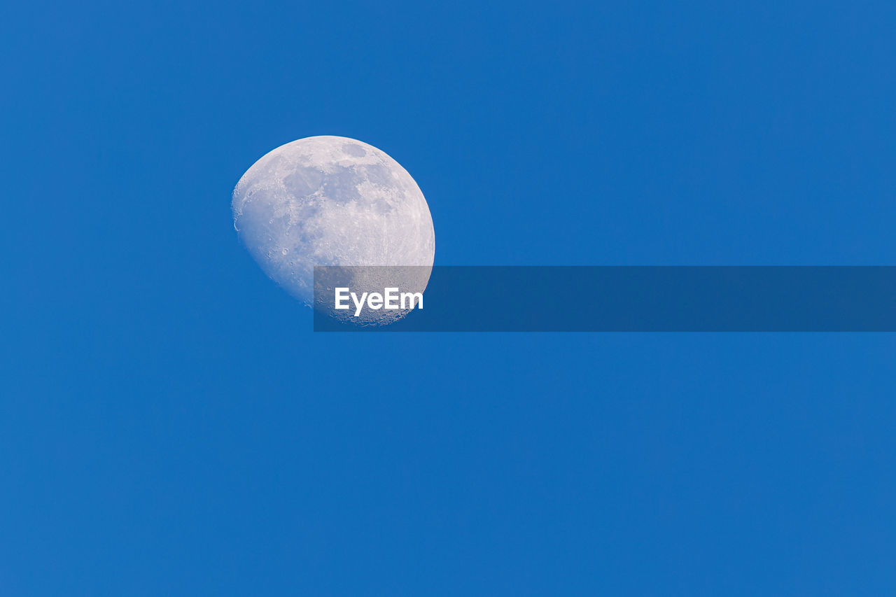 Low angle view of moon in clear blue sky