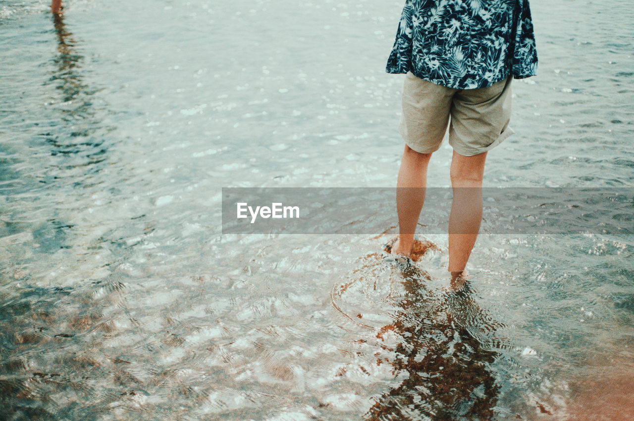 Low section of person standing in shallow water