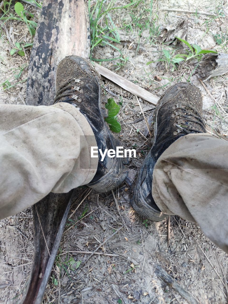 low section, human leg, shoe, high angle view, land, one person, personal perspective, day, nature, plant, footwear, lifestyles, outdoors, tree, men, human foot, standing, limb, forest, leisure activity, human limb, field, dirt, casual clothing