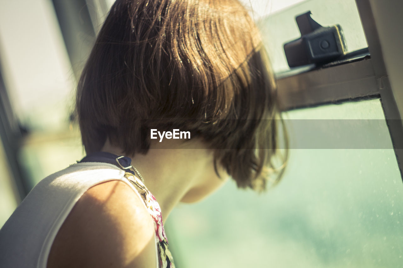 Rear view of girl looking through window