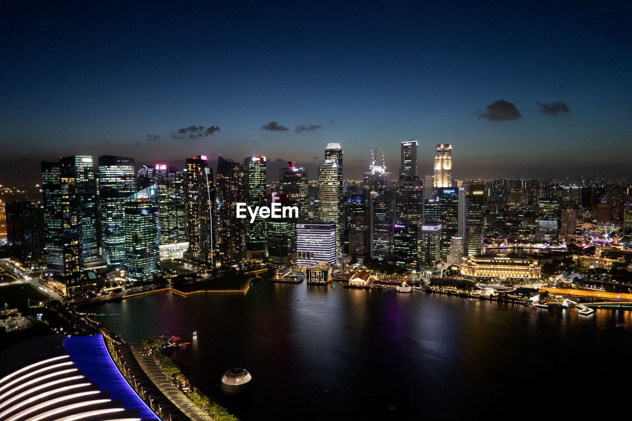 Illuminated city buildings against sky at night