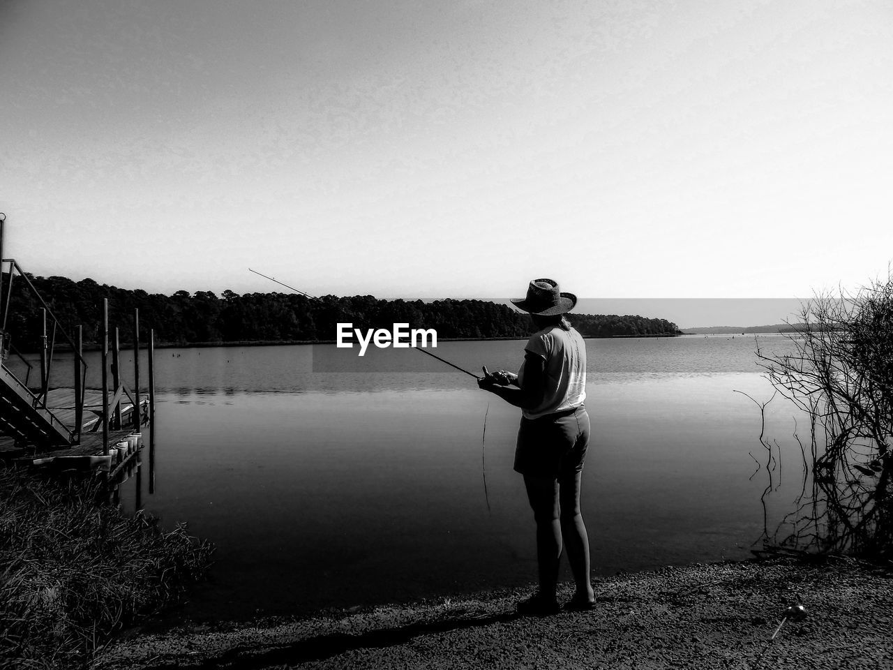 Woman fishing in lake against sky