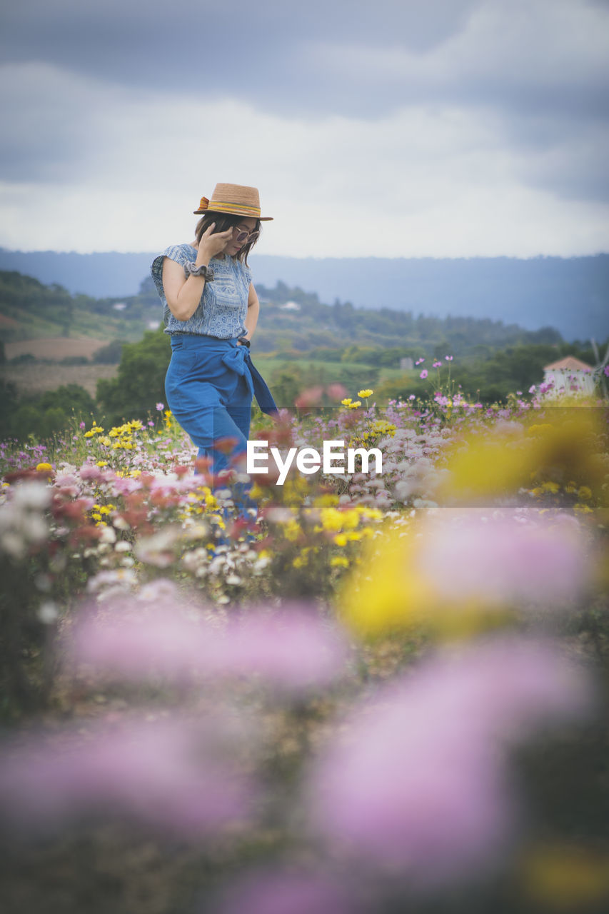 Beautiful woman standing in blooming flower garden