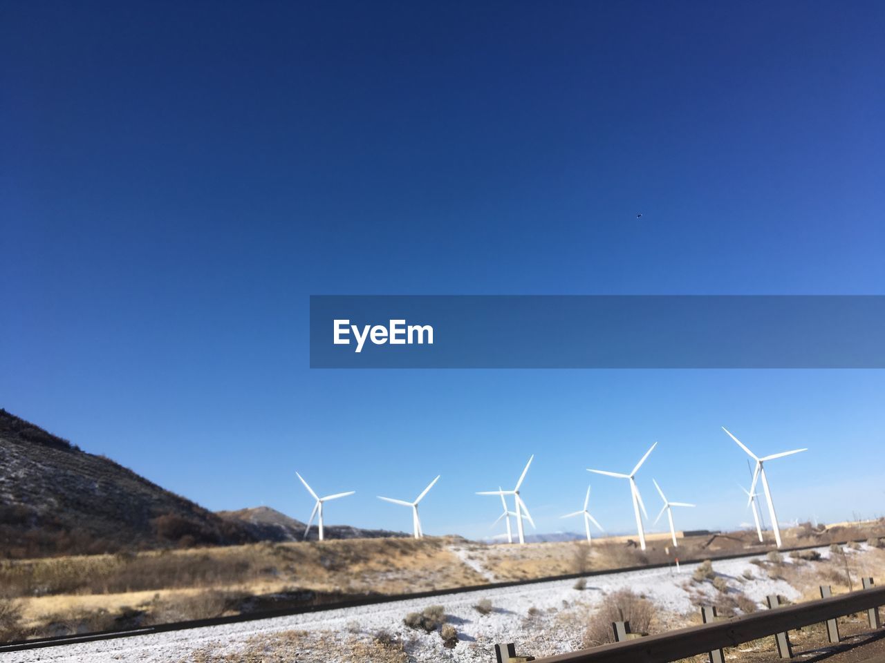 Wind turbines on field against clear blue sky