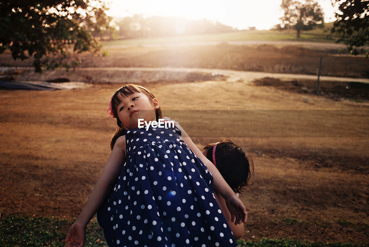 Girl looking away on field during sunset