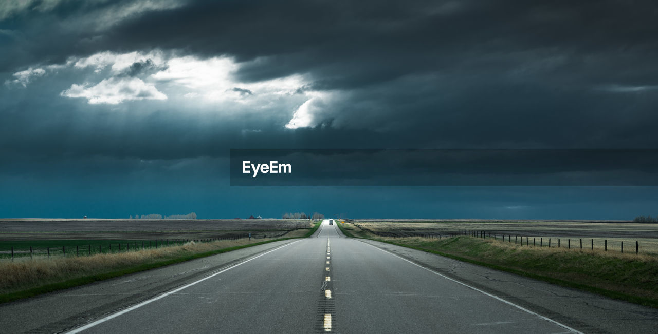 EMPTY ROAD AGAINST STORM CLOUDS