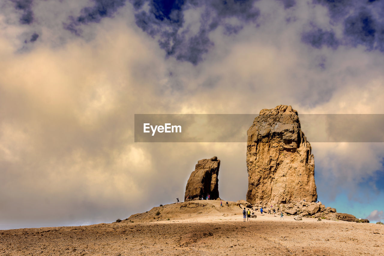 Statue on rock formation at desert against sky