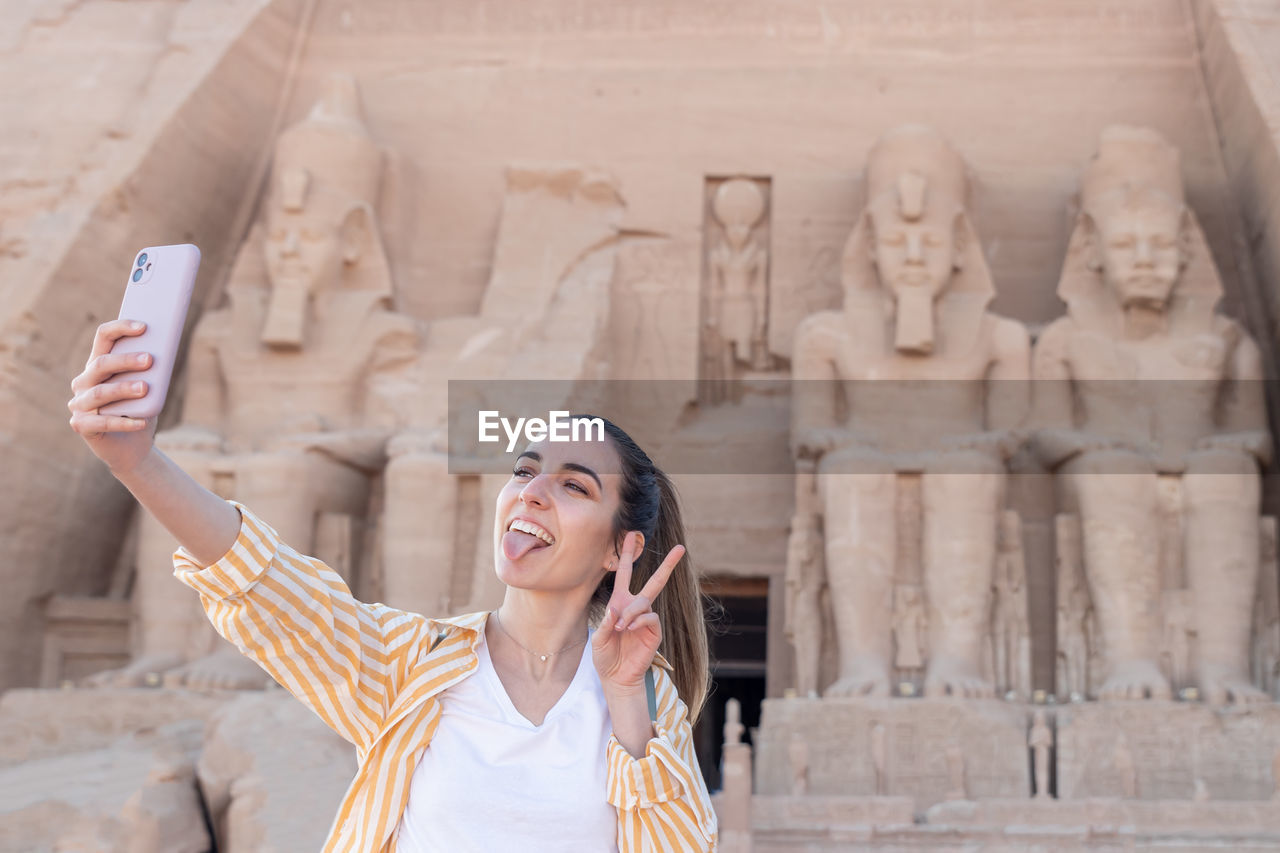 portrait of young woman standing against built structure