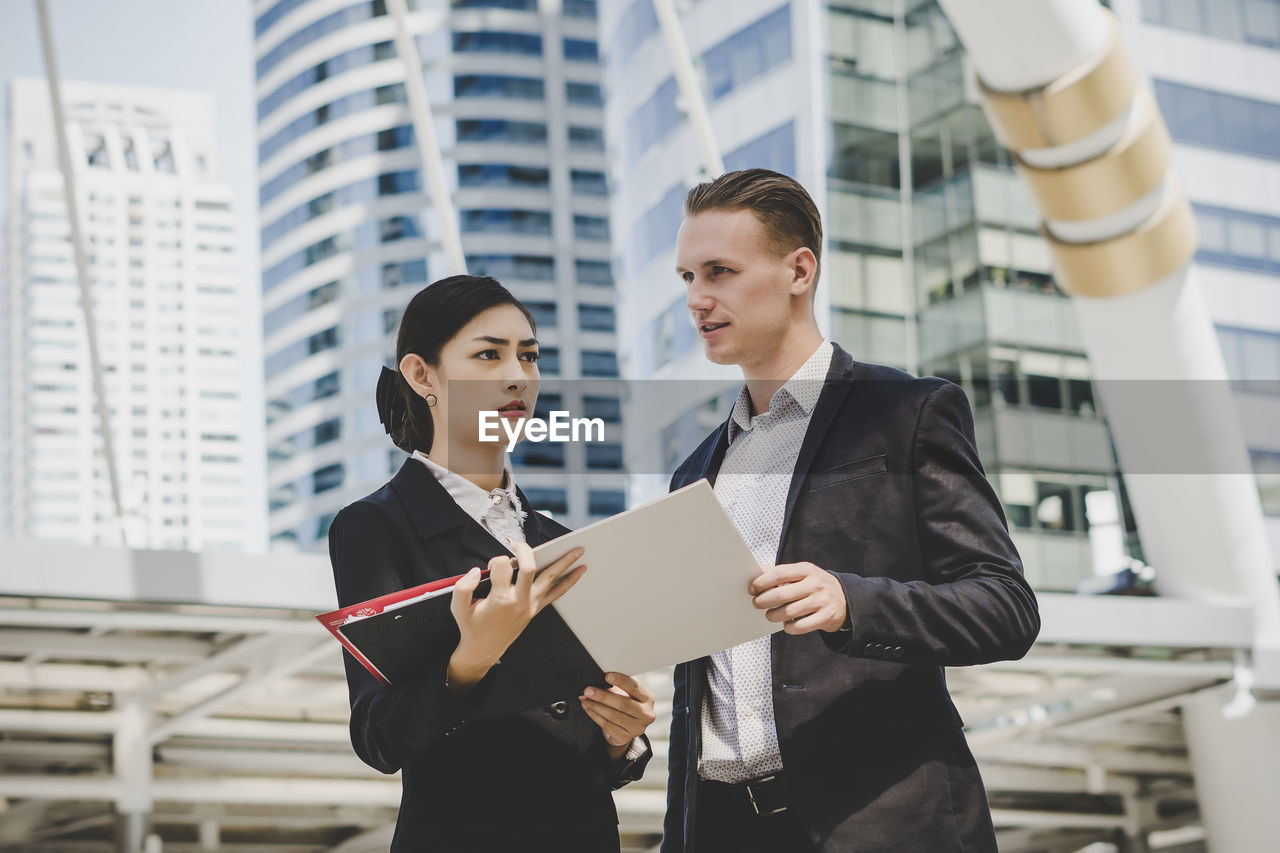 Low angle view of business people discussing while standing against building