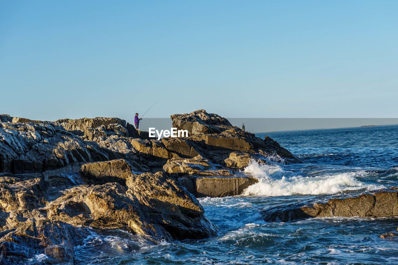 ROCK FORMATION IN SEA AGAINST CLEAR SKY