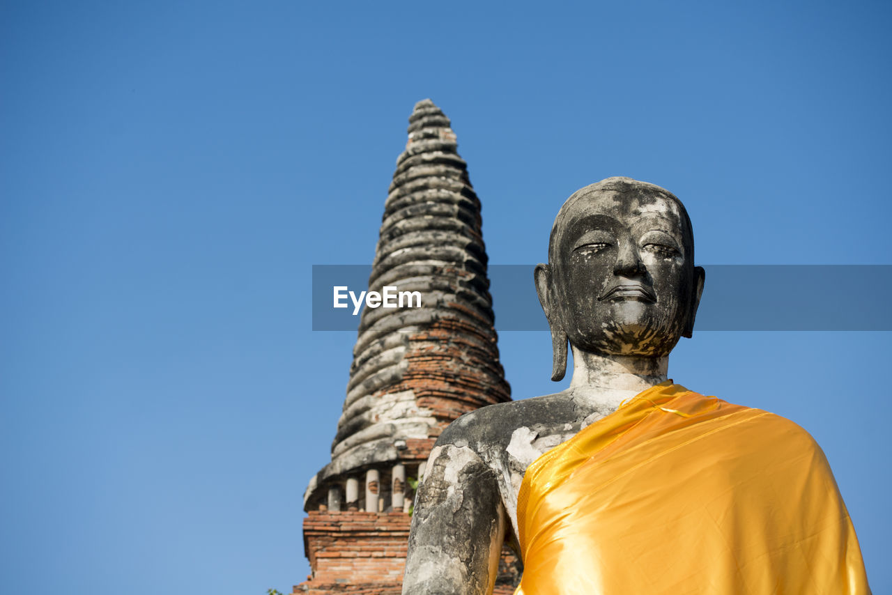 Low angle view of buddha statue at wat mahathat against clear sky